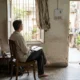 Traveler seated beside a homestay window with an open notebook on their lap.